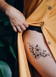 woman in orange button up shirt with black floral tattoo on her back