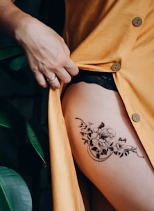 woman in orange button up shirt with black floral tattoo on her back