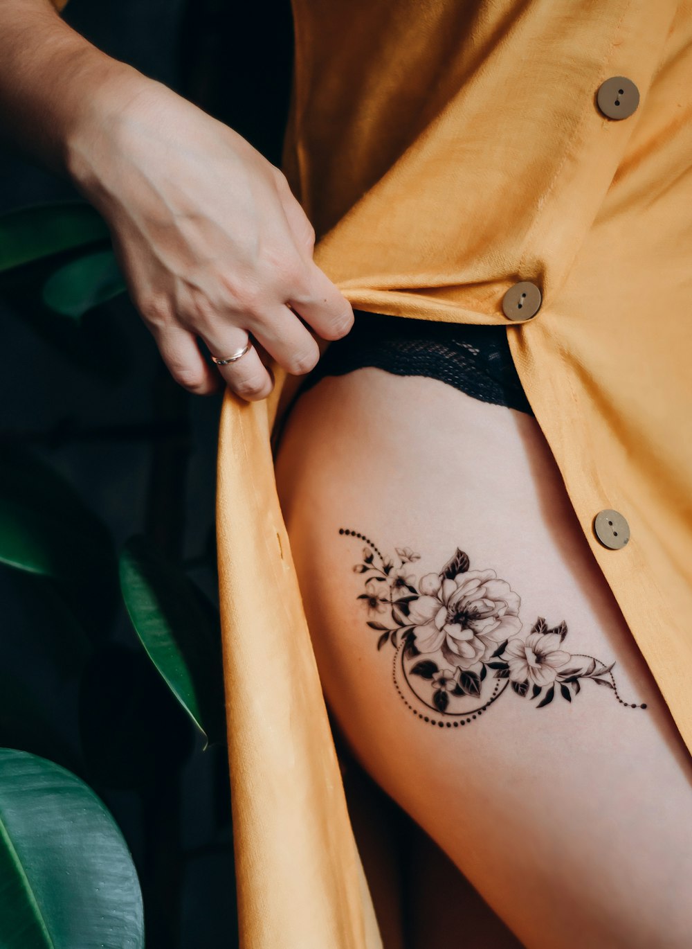 woman in orange button up shirt with black floral tattoo on her back