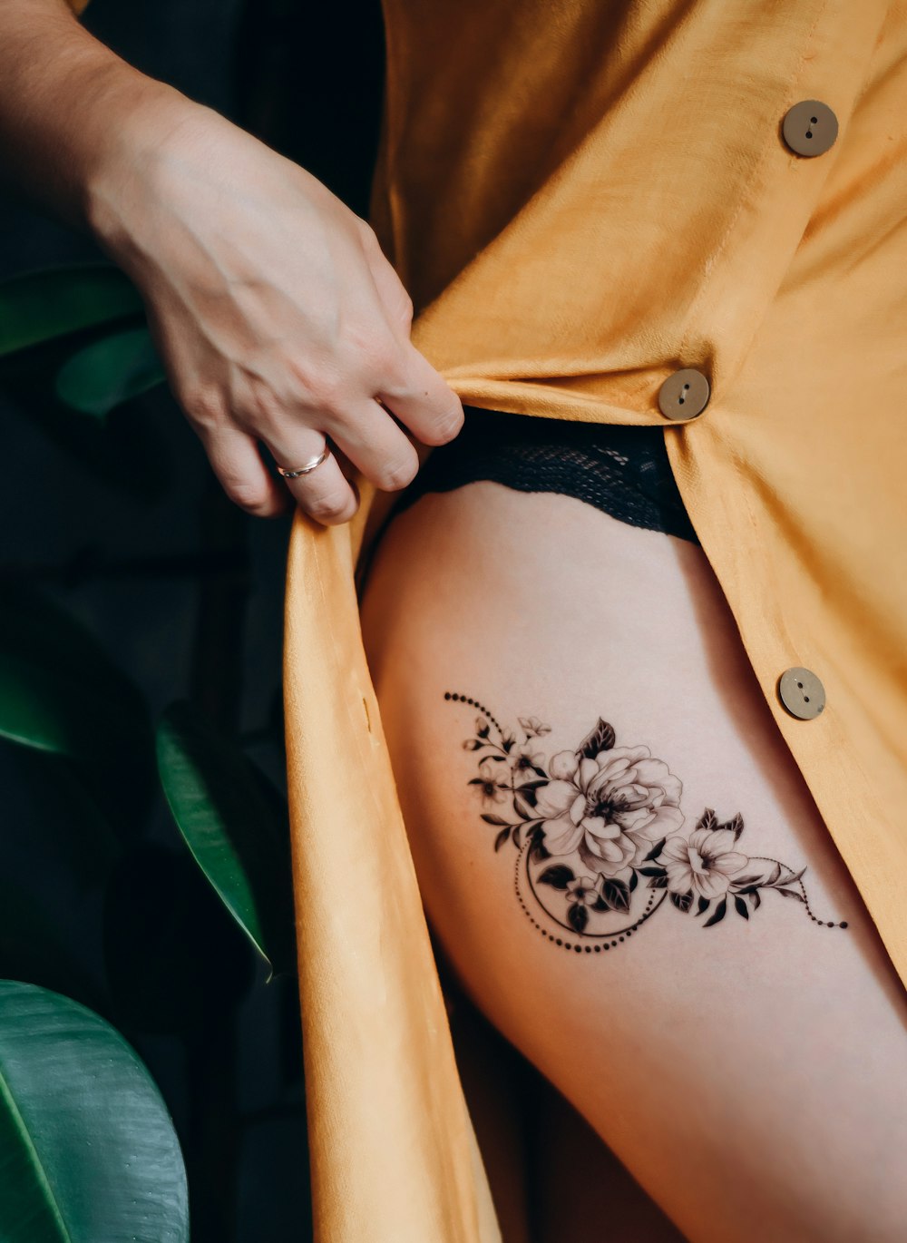 mulher na camisa laranja do botão acima com tatuagem floral preta em suas costas
