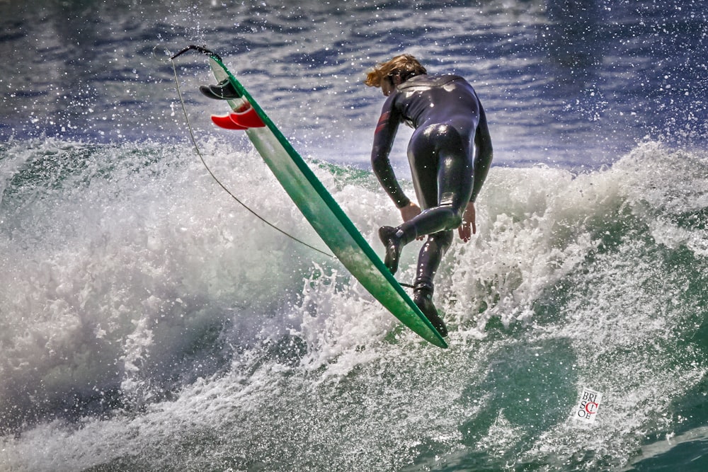 man in black wet suit riding green surfboard during daytime