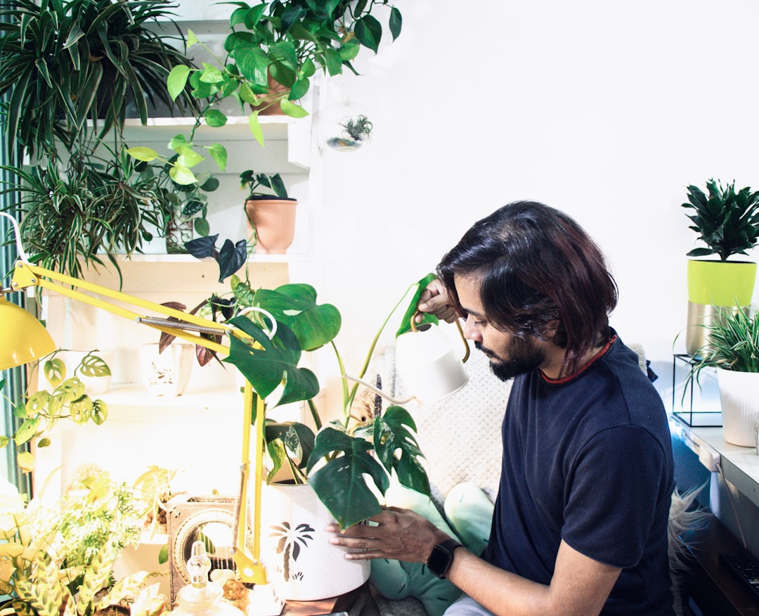 man in blue crew neck t-shirt sitting beside green plant