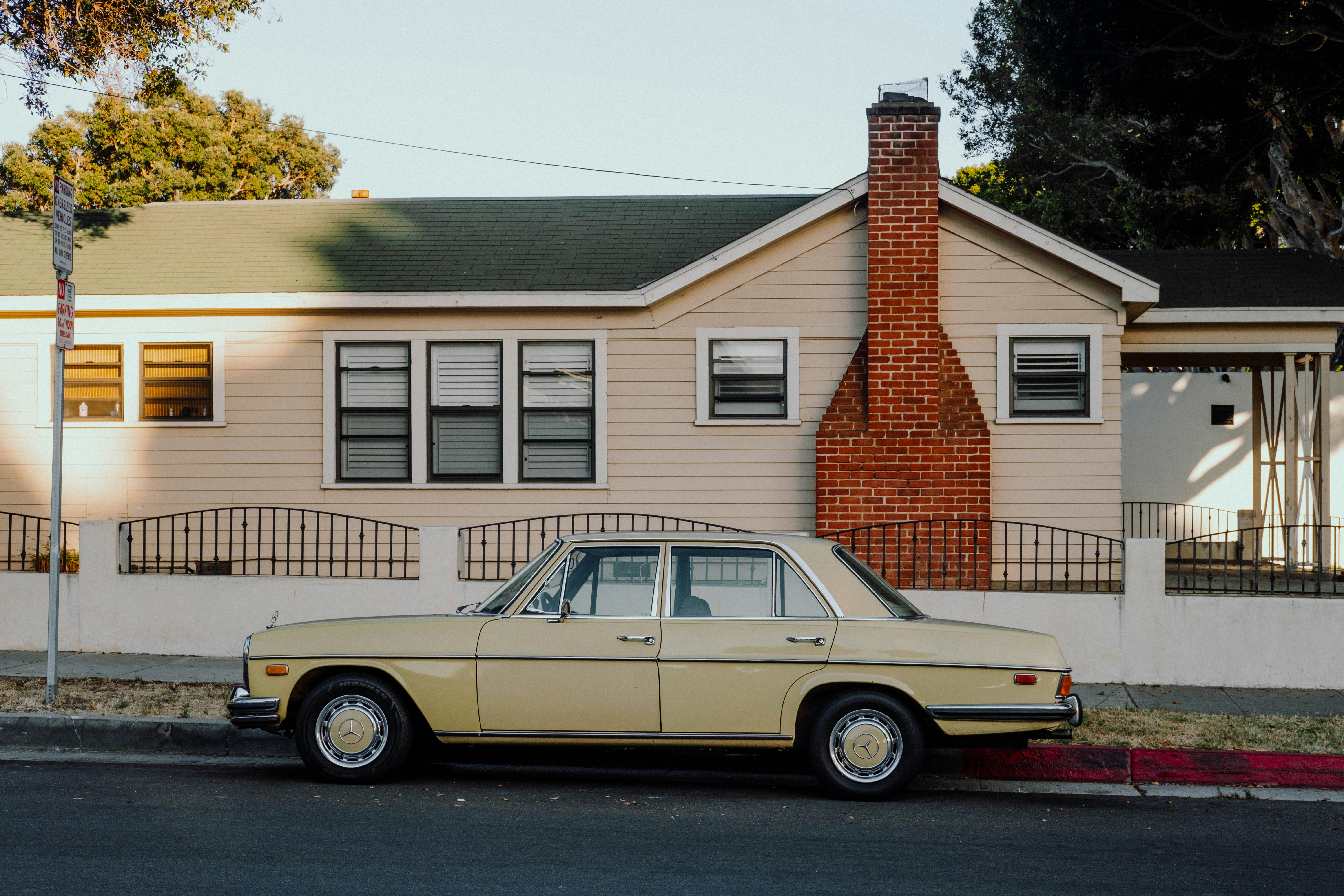 white sedan parked beside brown and white house