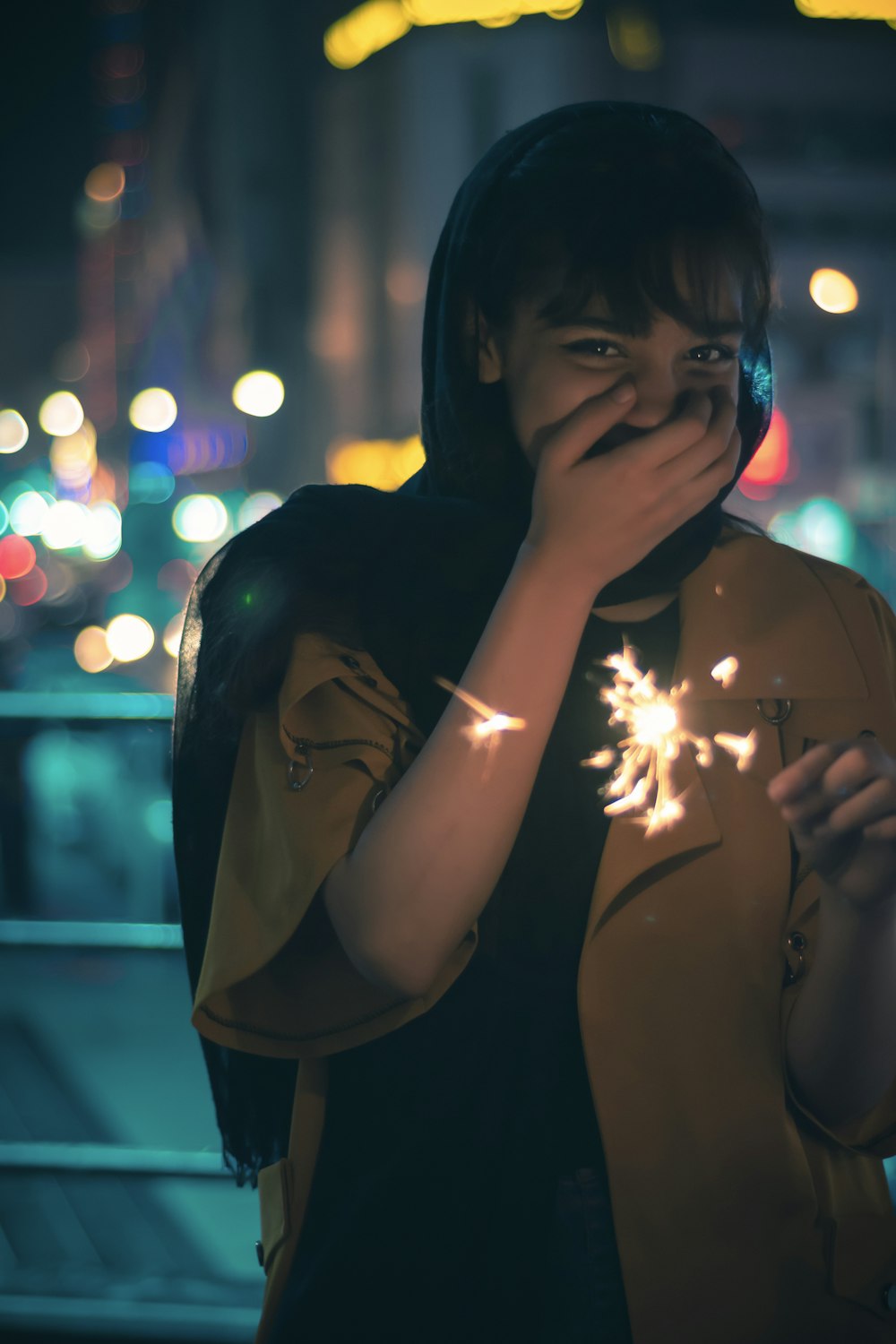 woman in black hijab holding lighted sparkler