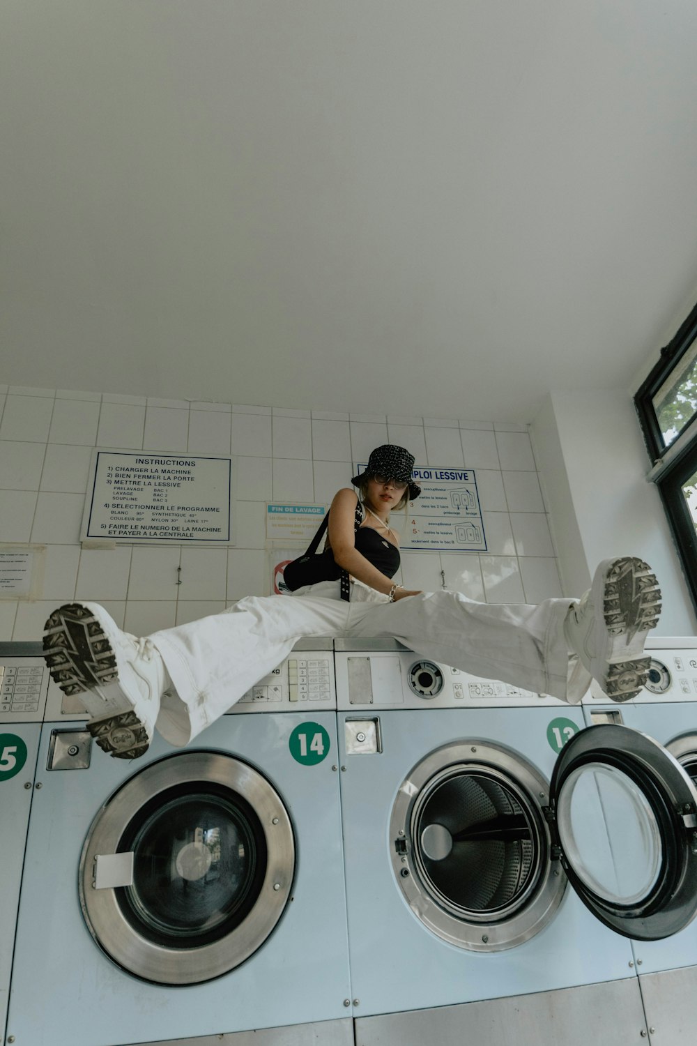 woman in black tank top sitting on white front load washing machine
