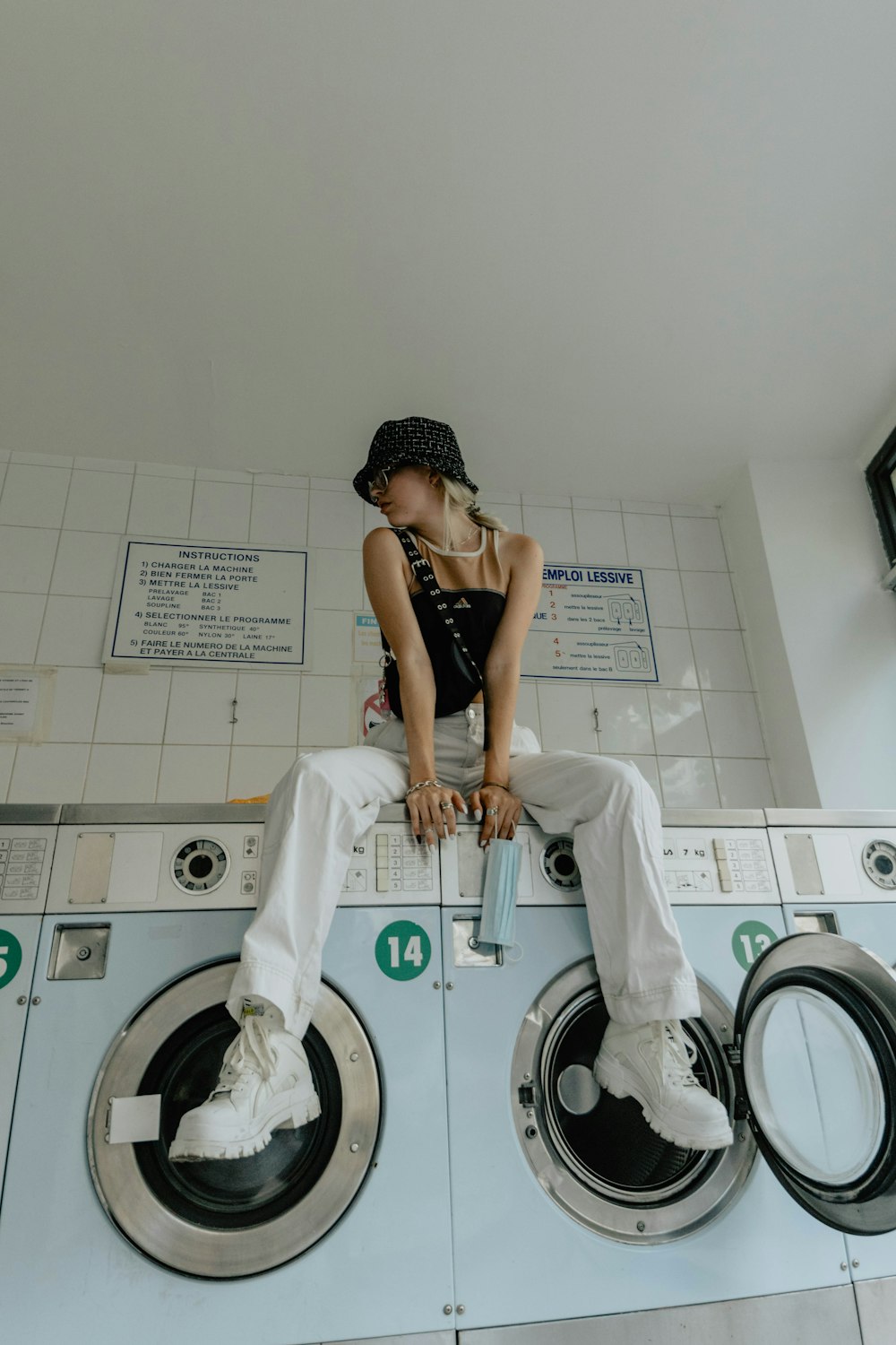woman in black brassiere and white pants sitting on white front load washing machine