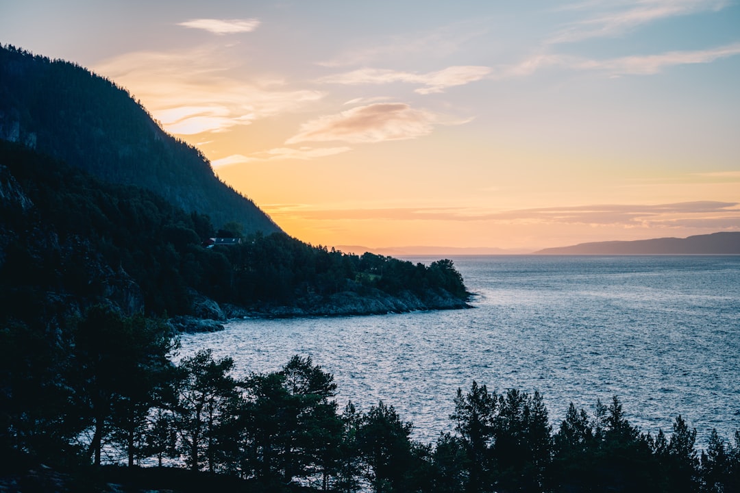 silhouette of mountain near body of water during sunset