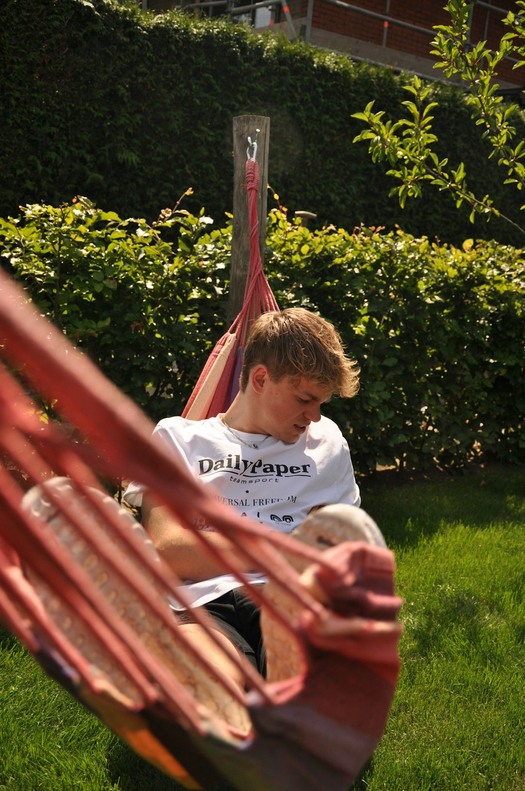 woman in white crew neck t-shirt sitting on red hammock during daytime