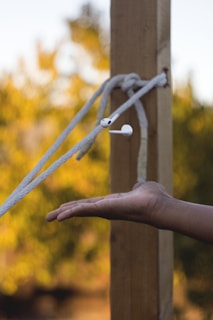 A pair of earbuds tangled gently on a denim jacket pocket outdoors.