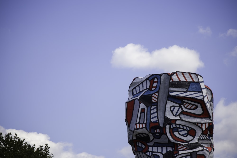 red blue and white wooden statue under white clouds during daytime
