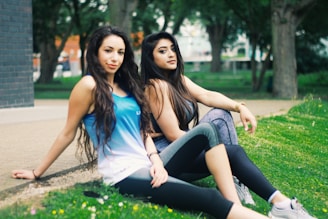 2 women sitting on green grass field during daytime