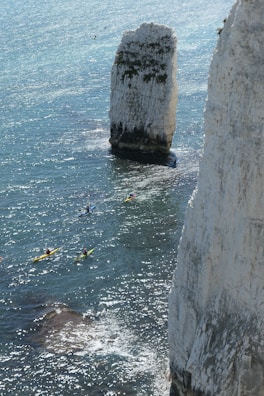 Kayakers paddling near a secluded beach with crystal-clear water and dramatic limestone formations.