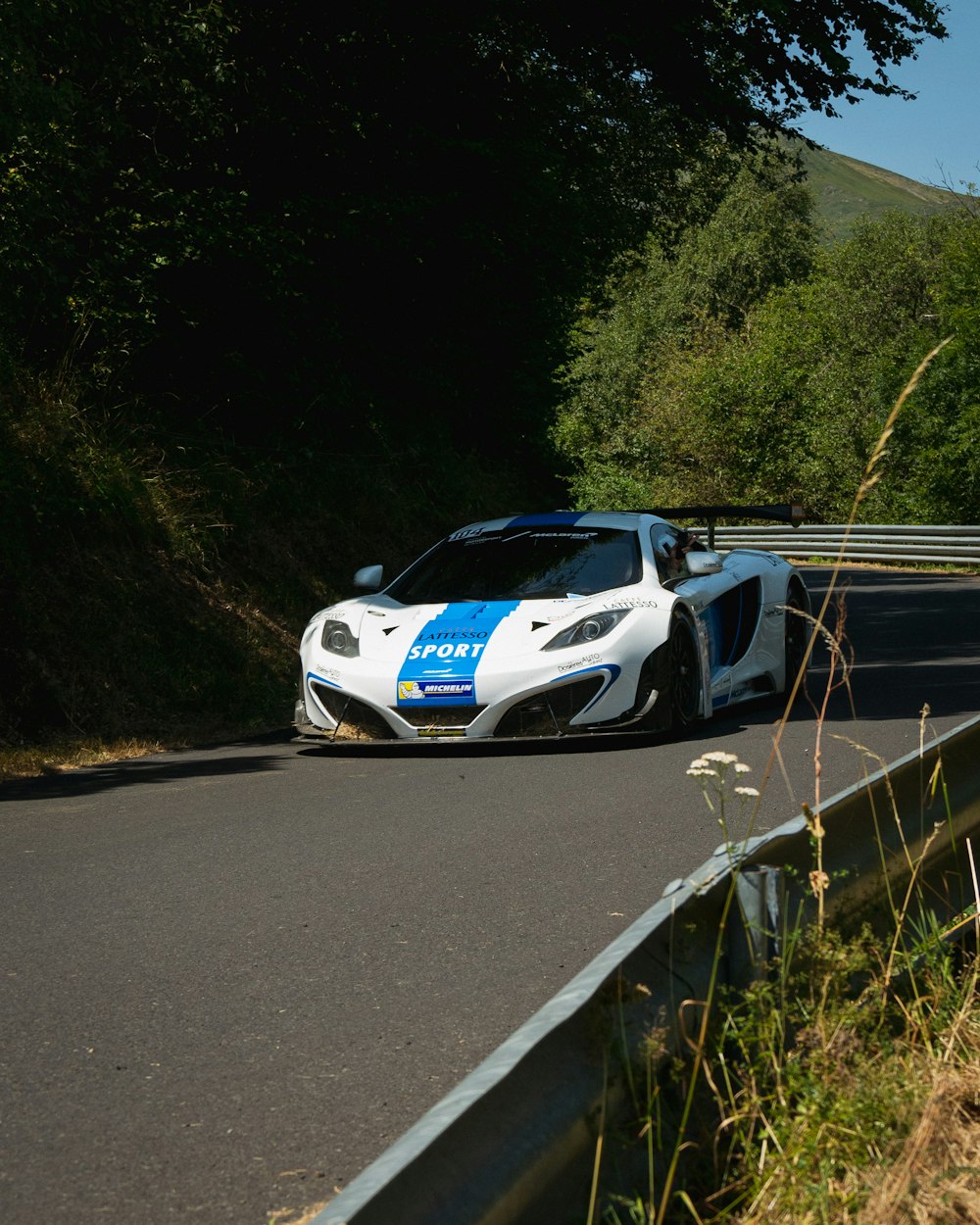 a white and blue sports car driving down a road
