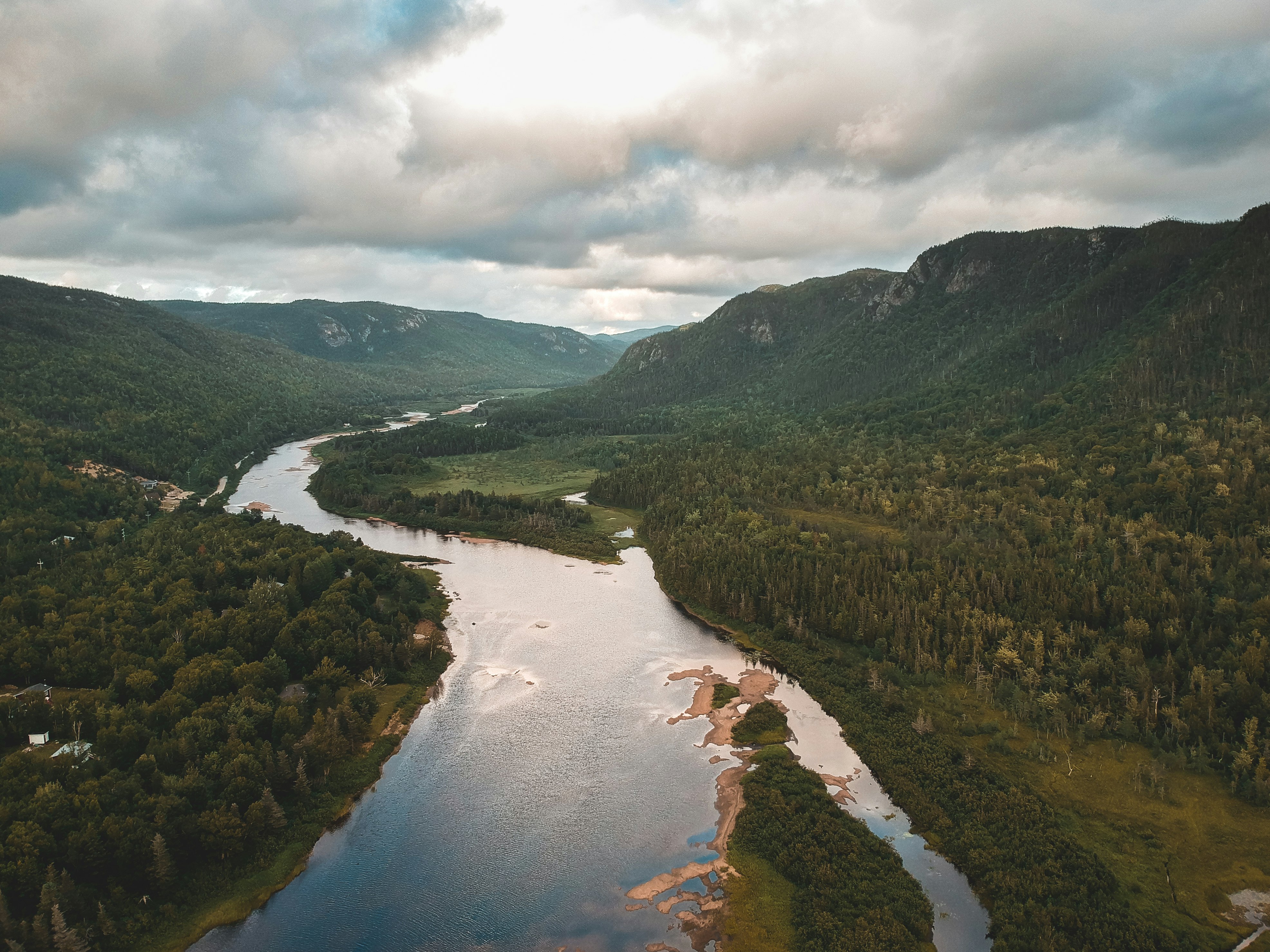 green mountains and river under white clouds during daytime