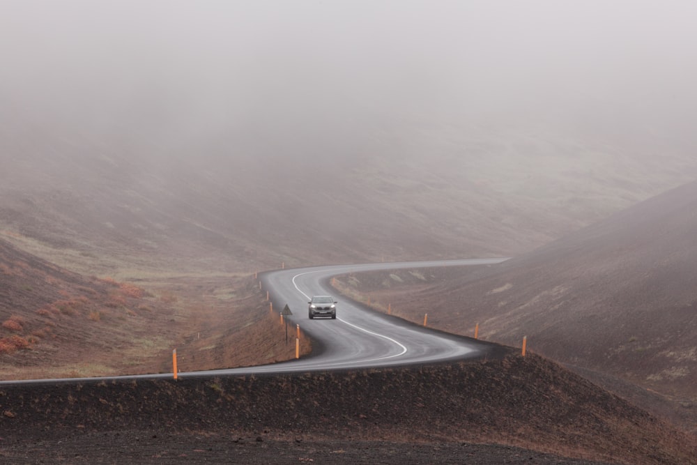 gray concrete road in the middle of foggy mountains