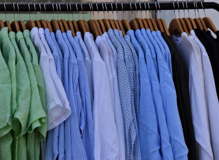 white blue and gray clothes hanging on brown wooden rack