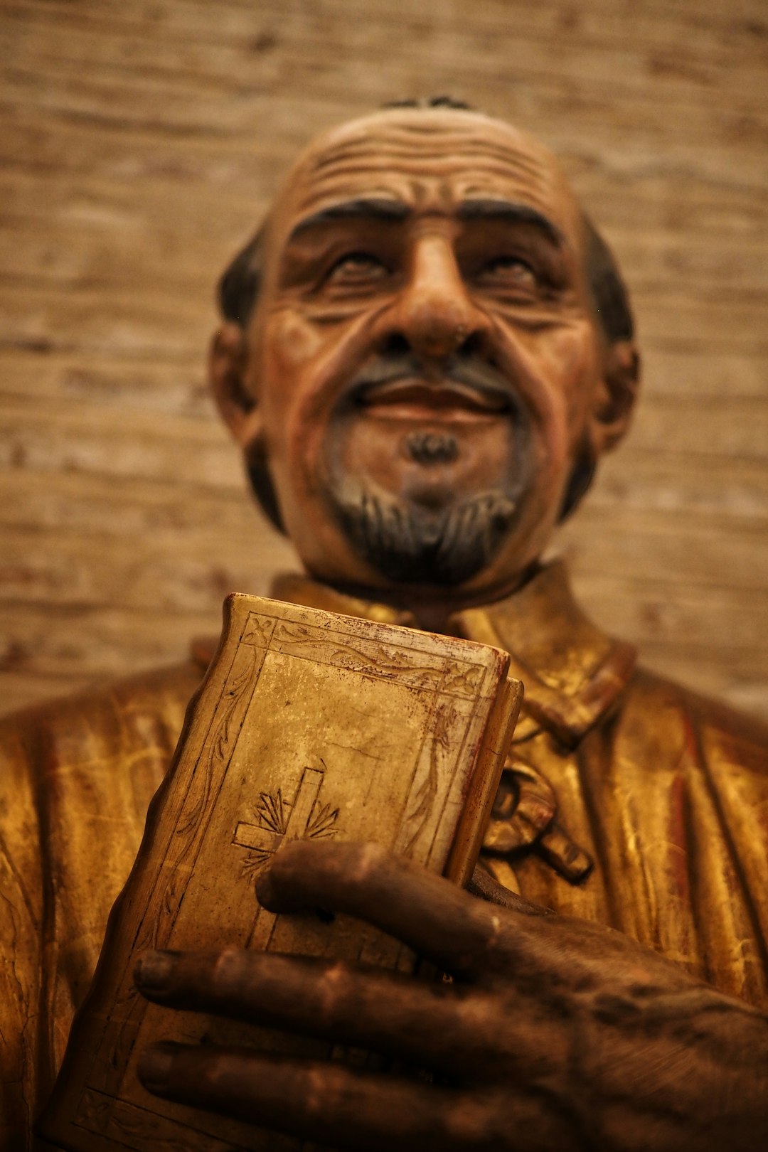 man in brown dress shirt holding book figurine
