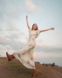 A woman dancing freely in an open field at sunset, symbolizing liberation.