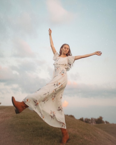 A woman dancing freely in an open field at sunset, symbolizing liberation.
