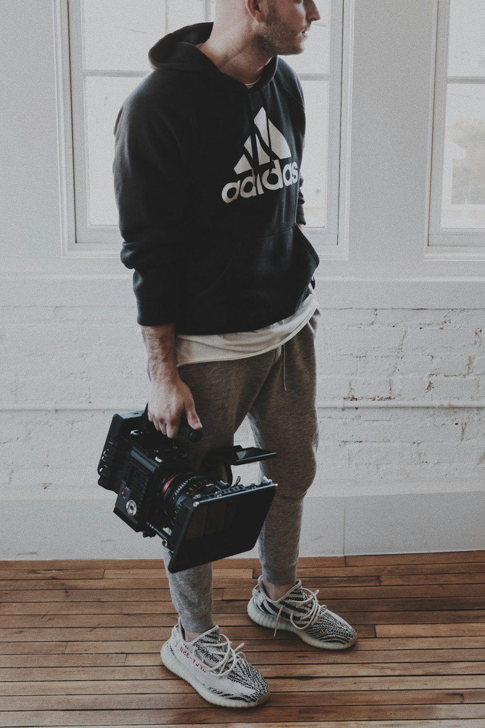 Hombre con camisa adidas en blanco y negro y pantalones marrones