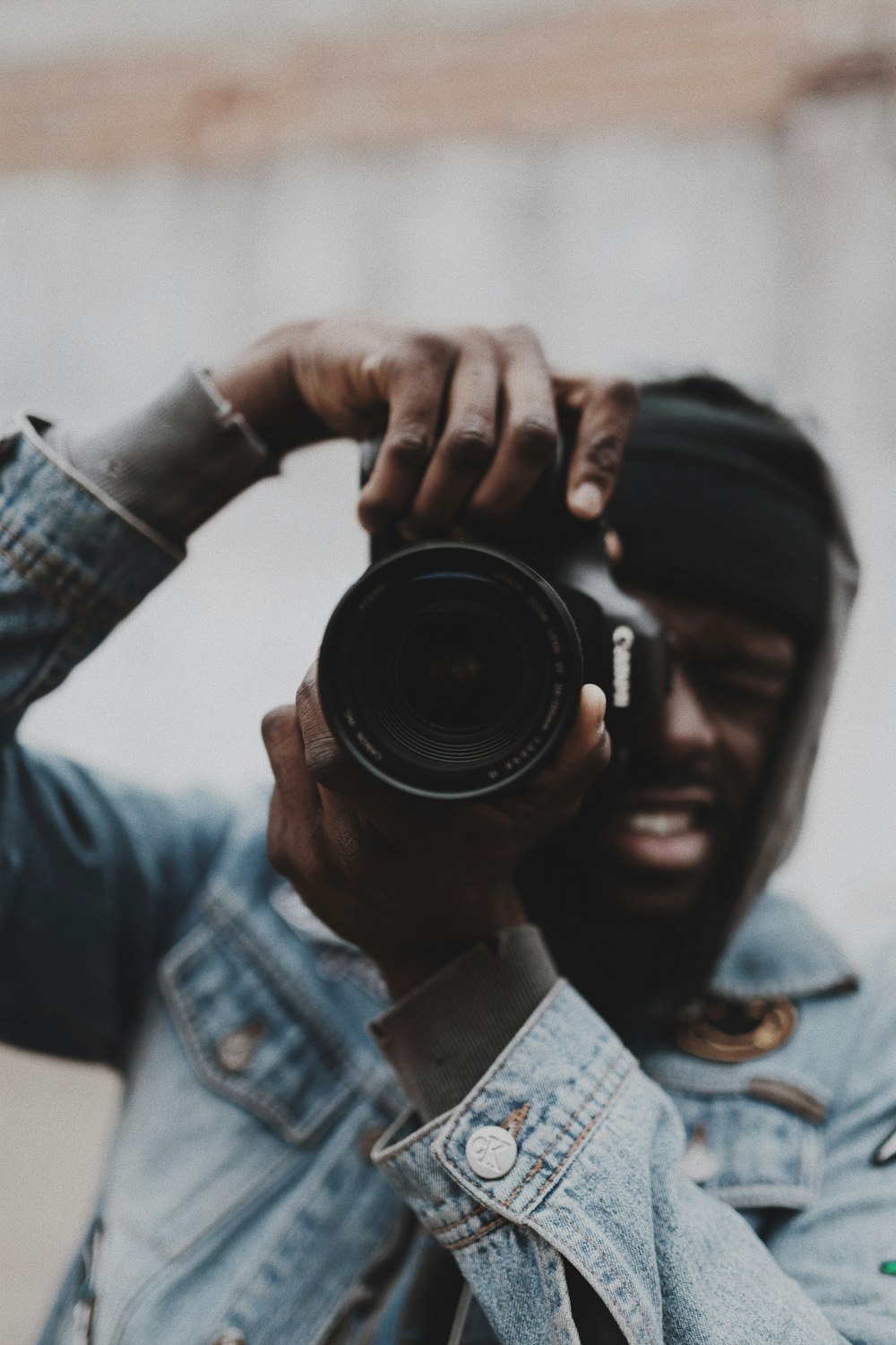 man in blue denim jacket holding black camera