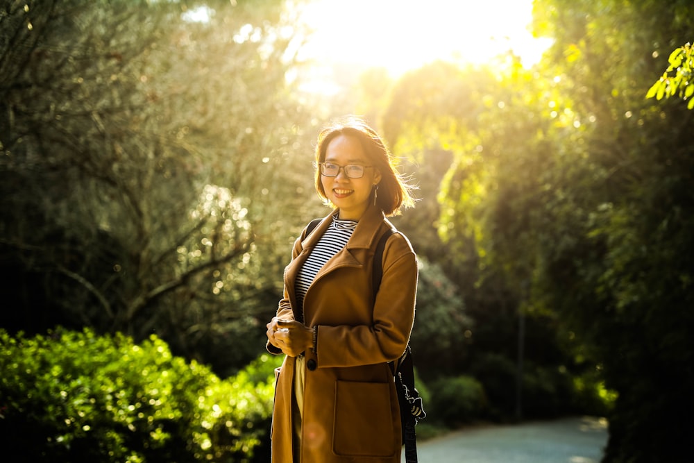 woman in brown coat standing on road during daytime