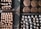 Trays filled with freshly baked cookies arranged neatly on a checkered floor. The cookies vary in shape and size, some dusted with powdered sugar and others having a round, dome-like form. The textures of the cookies are visually appealing, with some showing cracks on their surfaces.