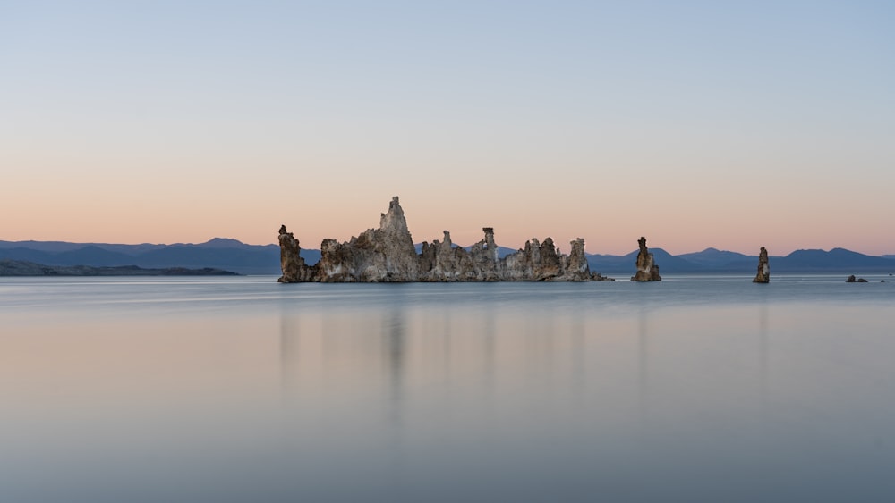 people sitting on rock formation in the middle of the sea