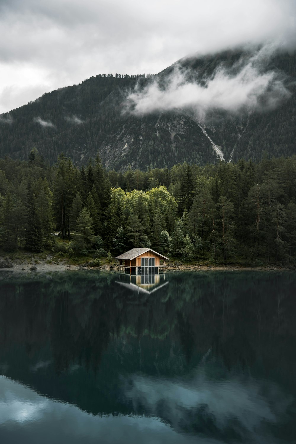 Casa de madera marrón cerca del lago y árboles verdes durante el día