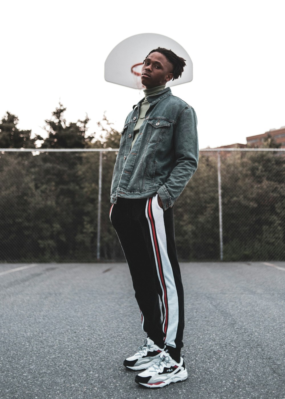 man in blue denim jacket and black pants wearing white cowboy hat standing on road during