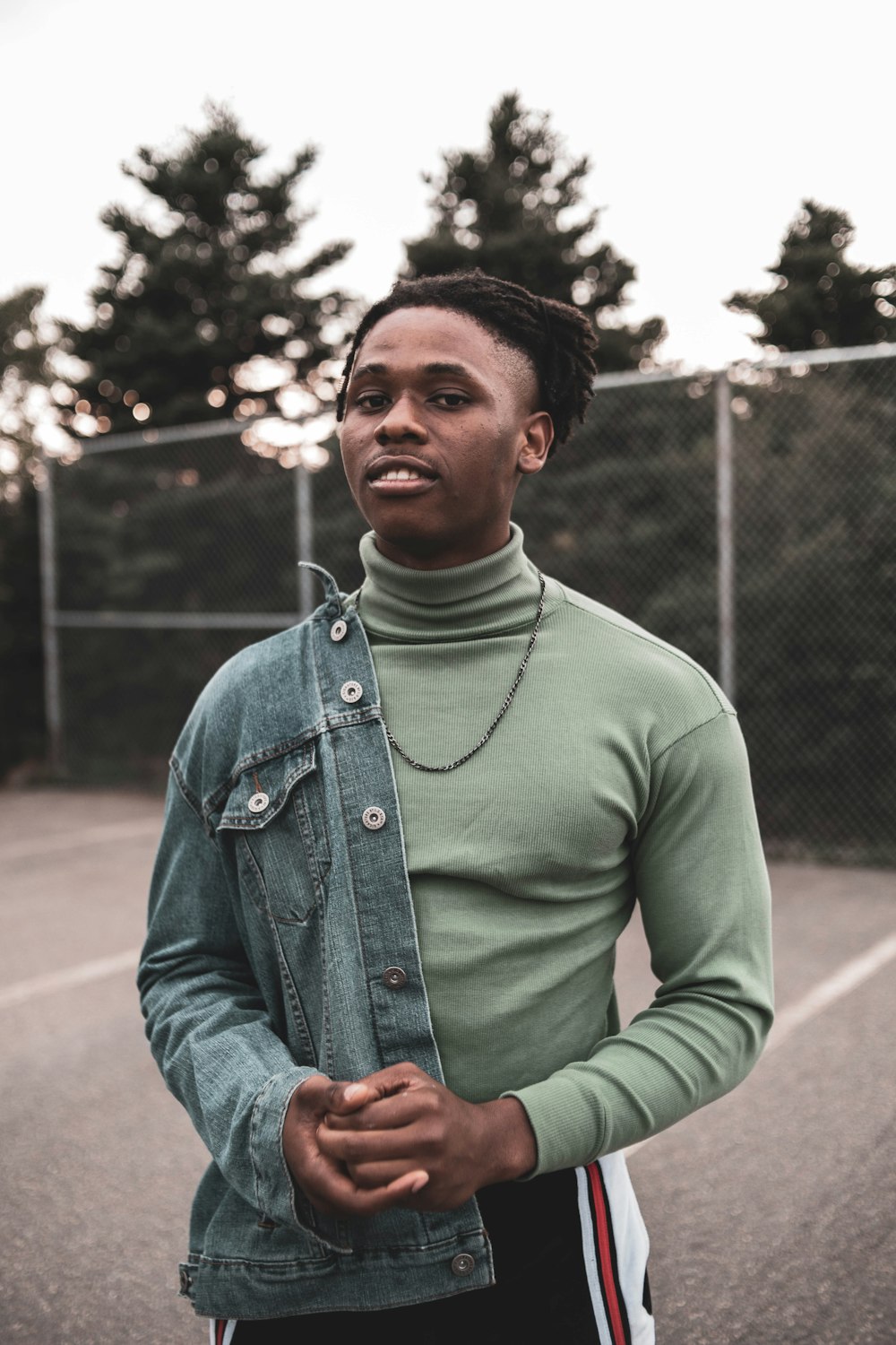 man in green crew neck long sleeve shirt standing near chain link fence during daytime