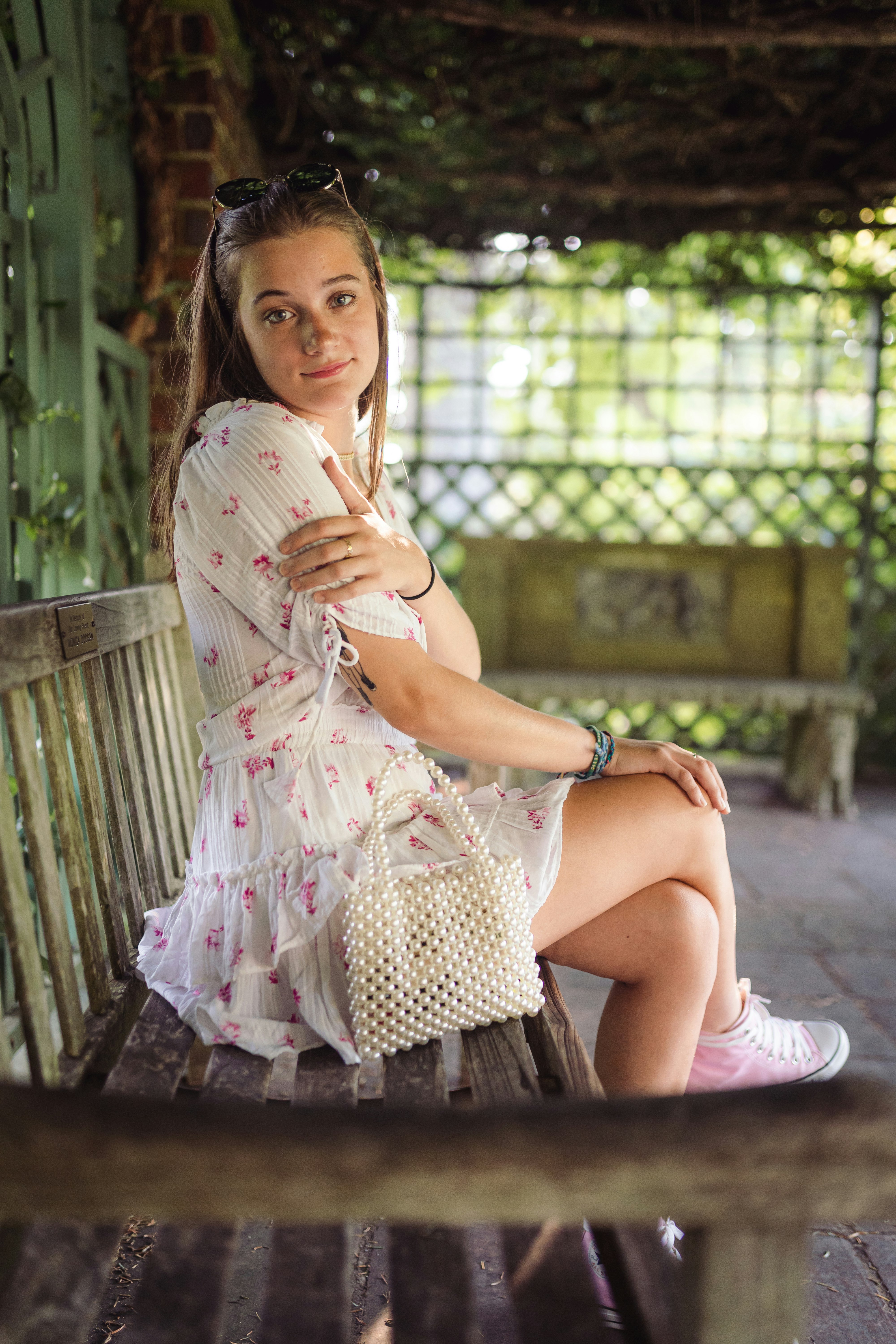 woman in white and pink polka dot dress sitting on brown wooden bench