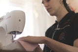 A sewing machine being used by a smiling woman.