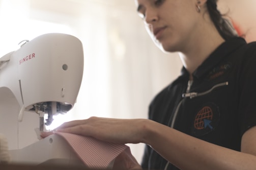 A sewing machine being used by a smiling woman.