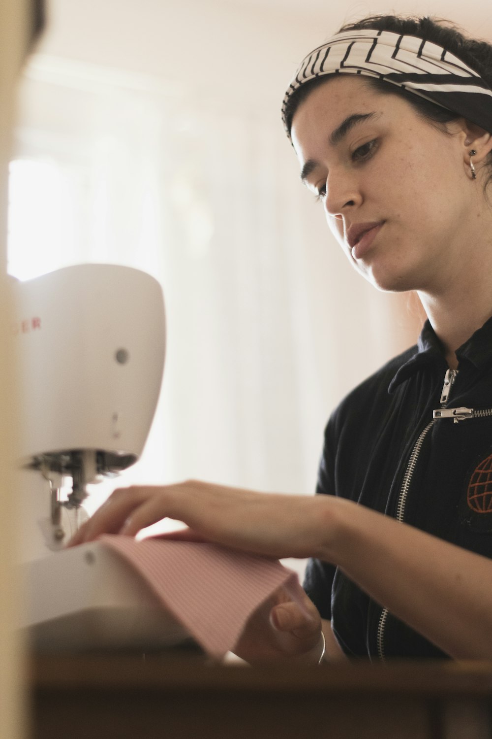 man in black polo shirt using white sewing machine