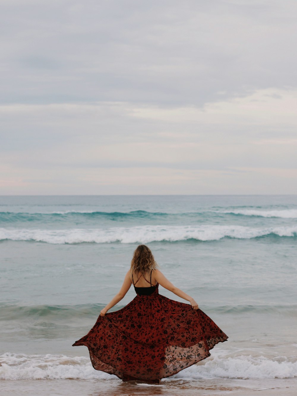 woman in black dress standing on seashore during daytime