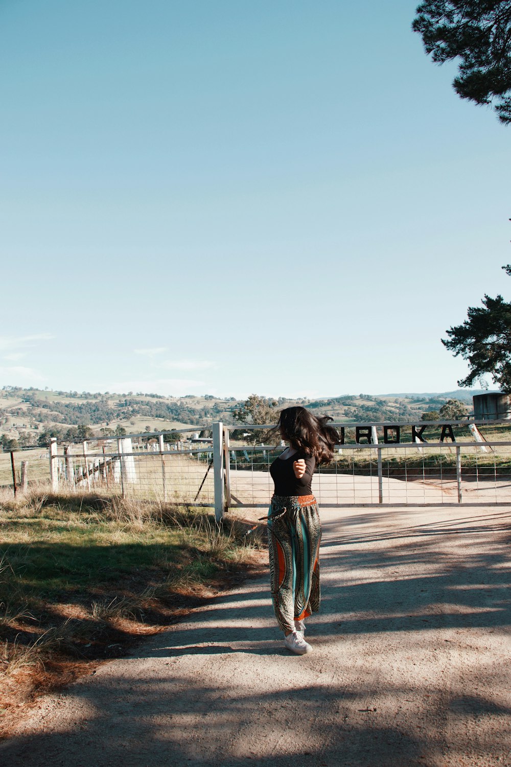 Femme en robe bleue et blanche debout sur un champ brun pendant la journée