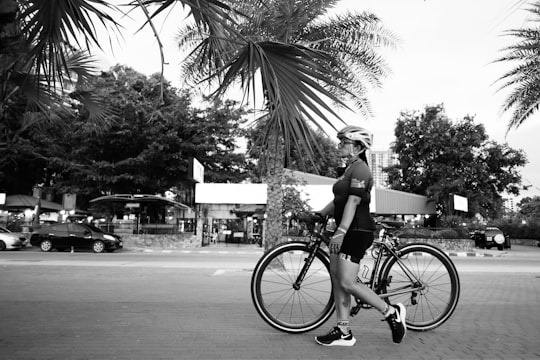 grayscale photo of woman riding bicycle on road in Jomtien Beach Thailand