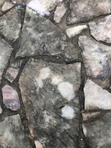 Close-up of a hand laying smooth stone pavers in a neat, patterned driveway.
