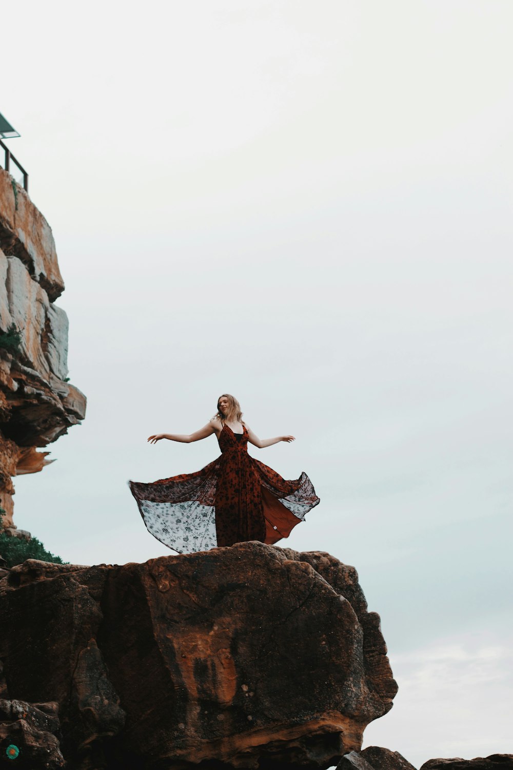 woman in black dress standing on rock formation during daytime