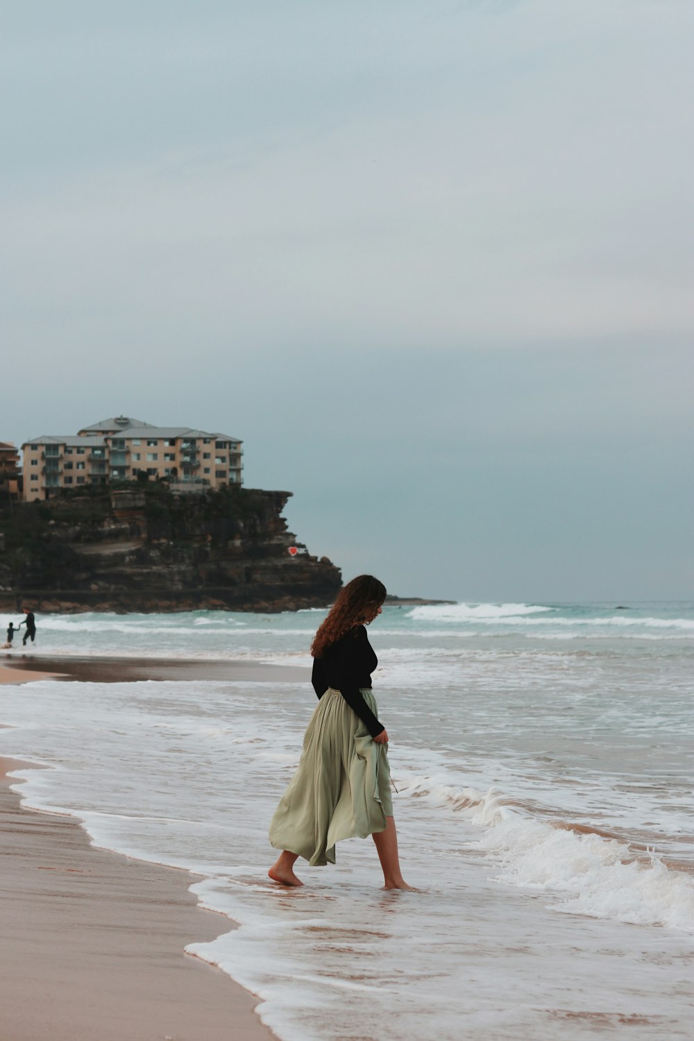 낮 동안 해변에 서 있는 흰 치마를 입은 여자