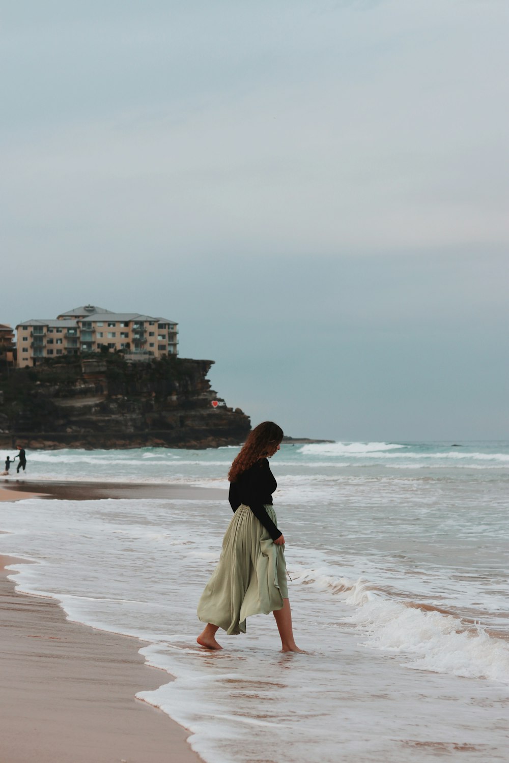 woman in white skirt standing on beach during daytime