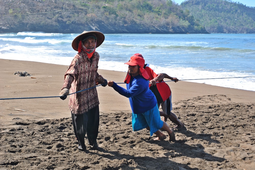 man in black and white plaid dress shirt holding girl in blue jacket on beach during