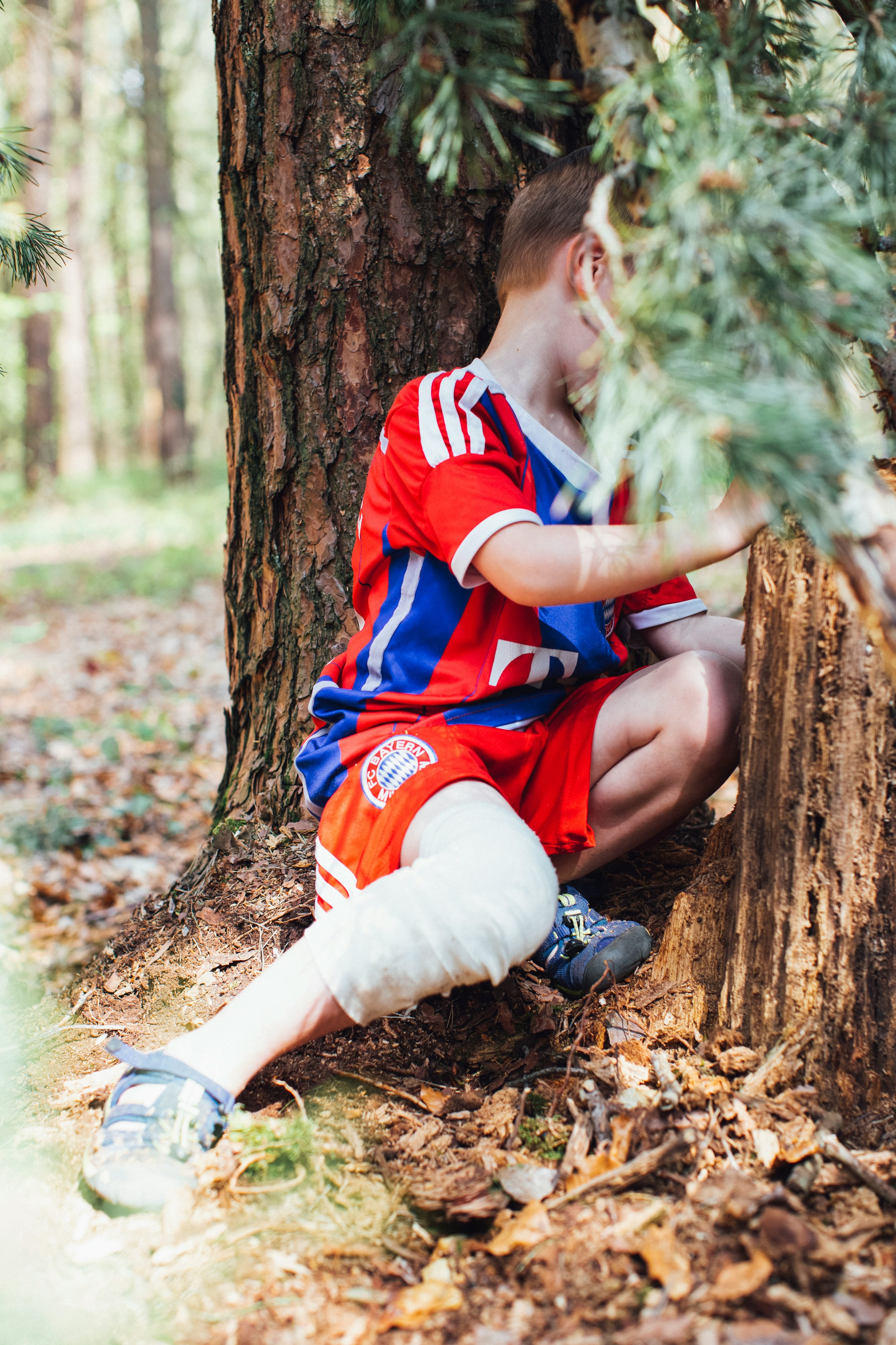 boy in red and blue polo shirt sitting on tree log