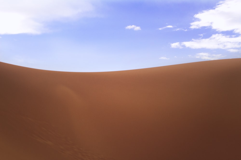 sable brun sous ciel bleu pendant la journée