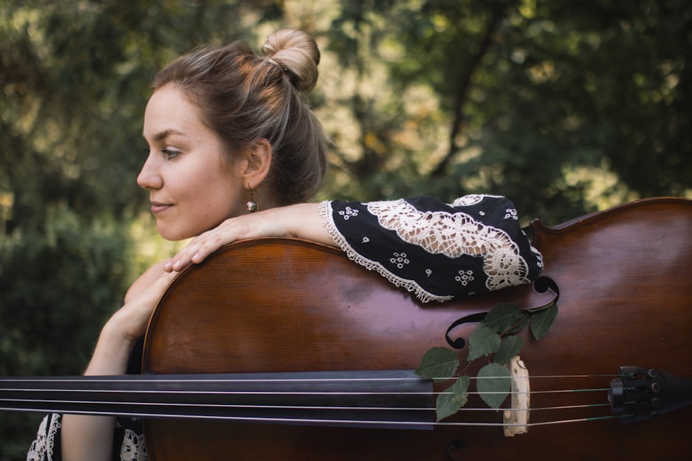 woman in black and white floral dress holding brown violin