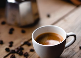 white ceramic mug with coffee on brown wooden table