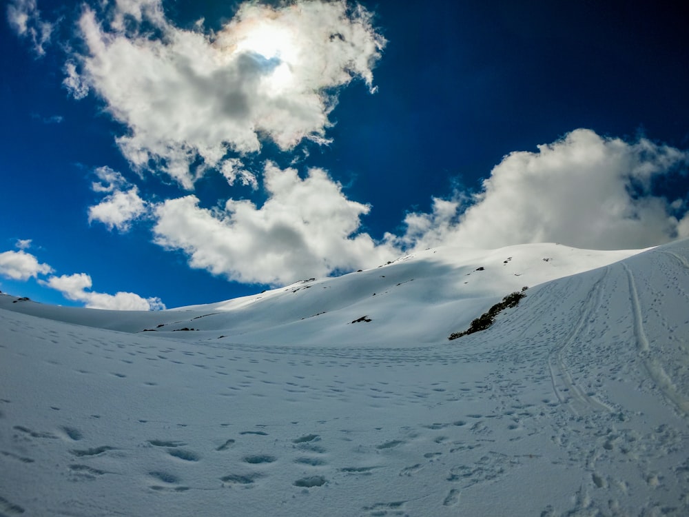 Montaña cubierta de nieve blanca bajo cielo azul y nubes blancas durante el día
