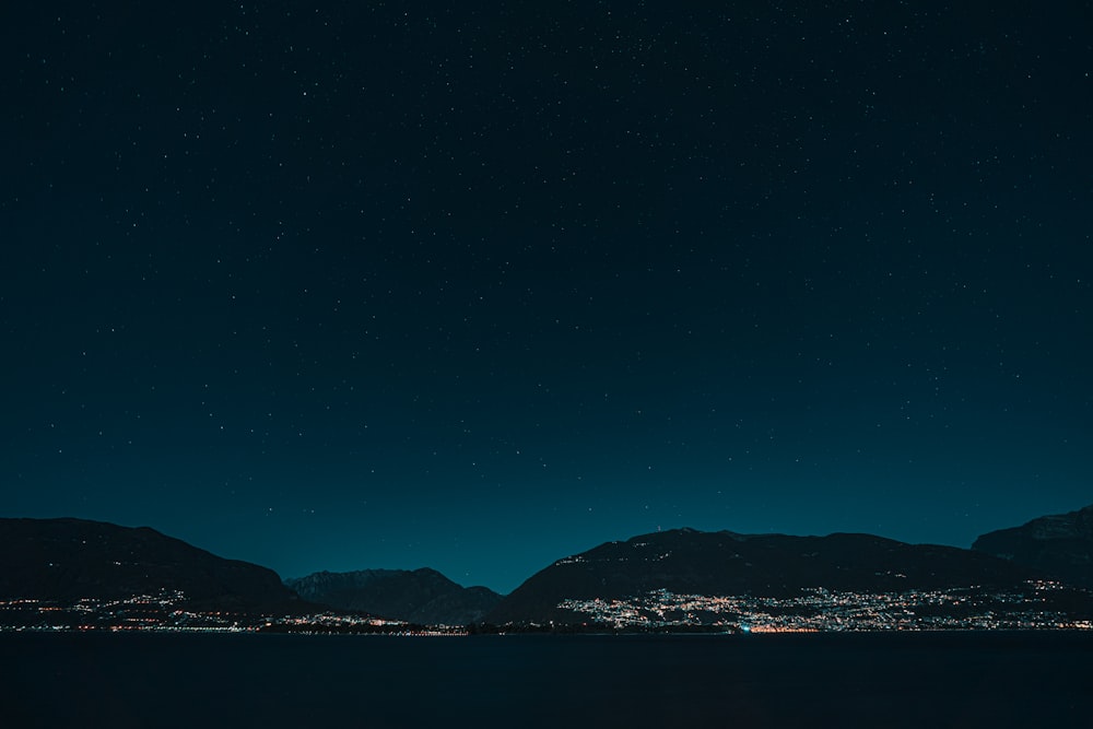 Silueta de la montaña cerca del cuerpo de agua durante la noche