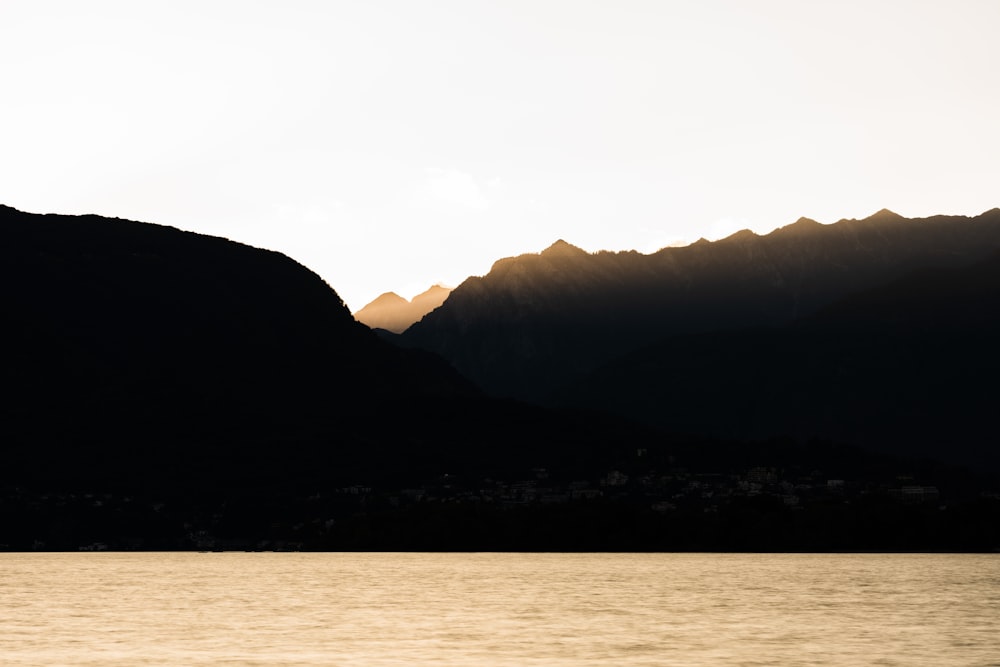 silhouette of mountains near body of water during daytime